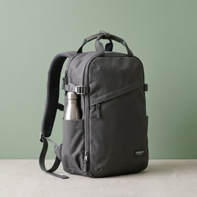 Gray canvas everyday backpack with a water bottle in the side pocket